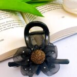 گیره مو مشکی گلدار کنار کتاب